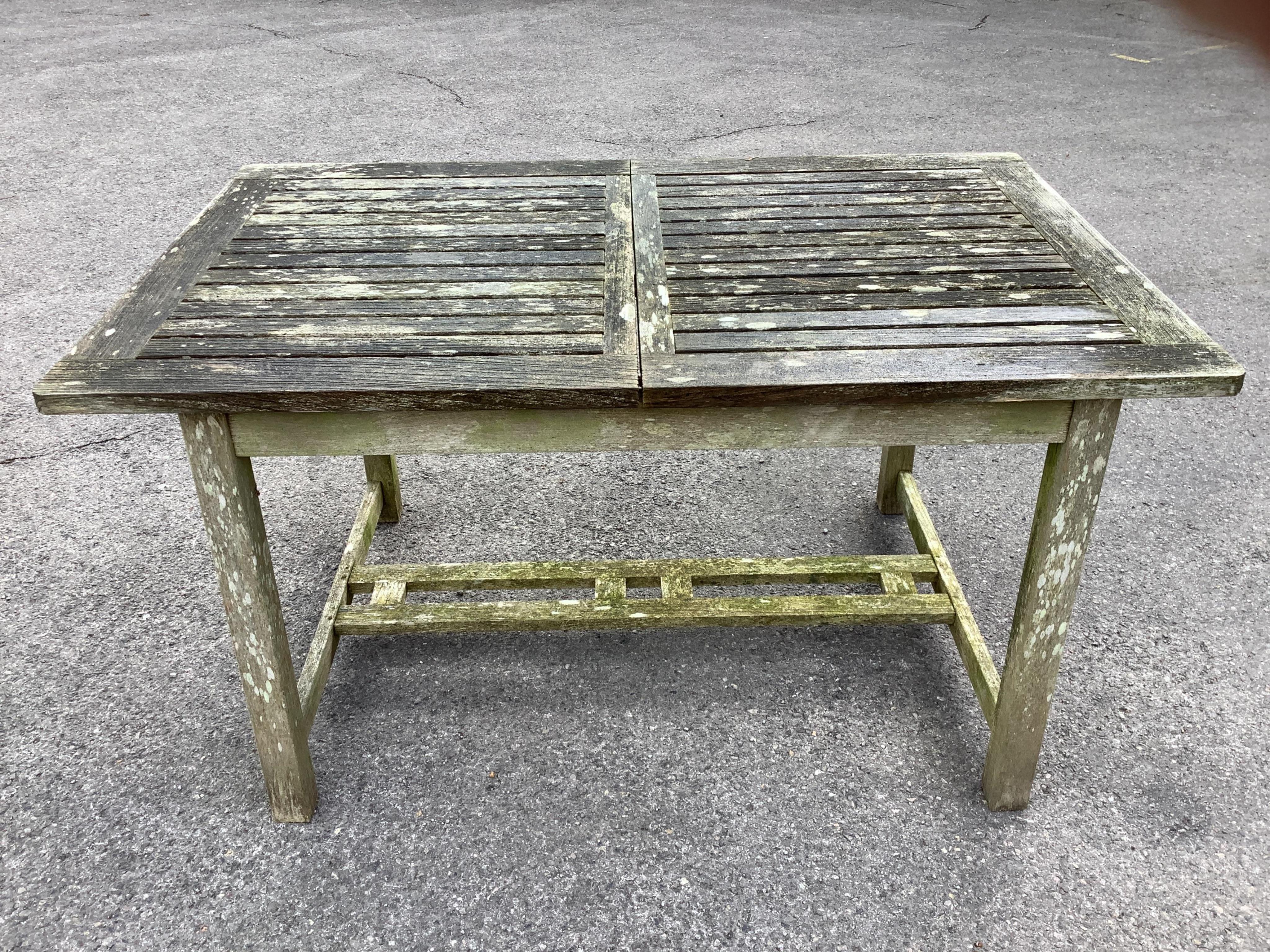 A Westminster rectangular weathered teak extending garden table, width 140cm, depth 90cm, height 73cm, (leaves inoperable), together with a pair of teak folding garden chairs. Condition - fair